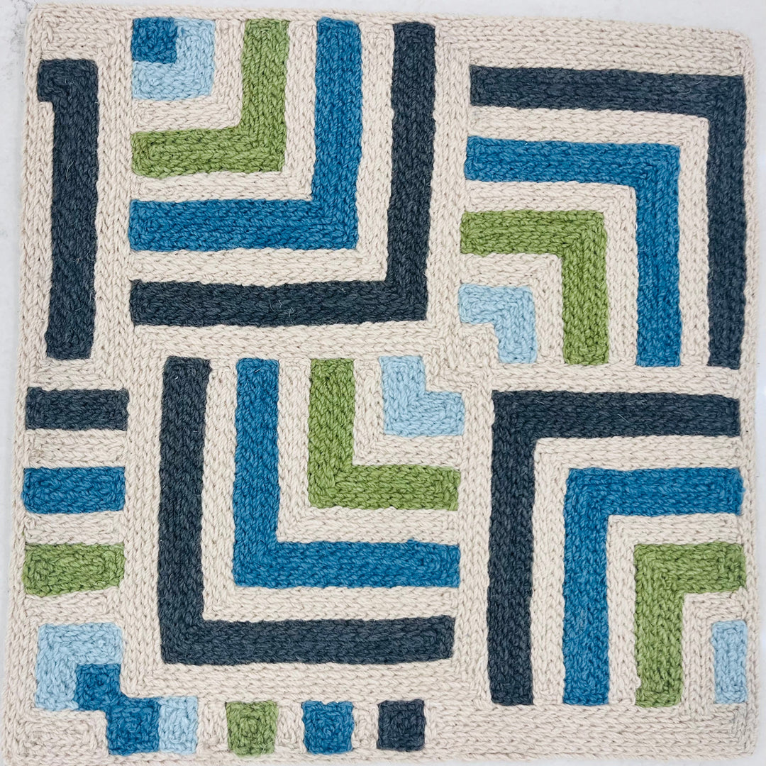 Geometric patterned rug with blue, green, and beige colors on a white background