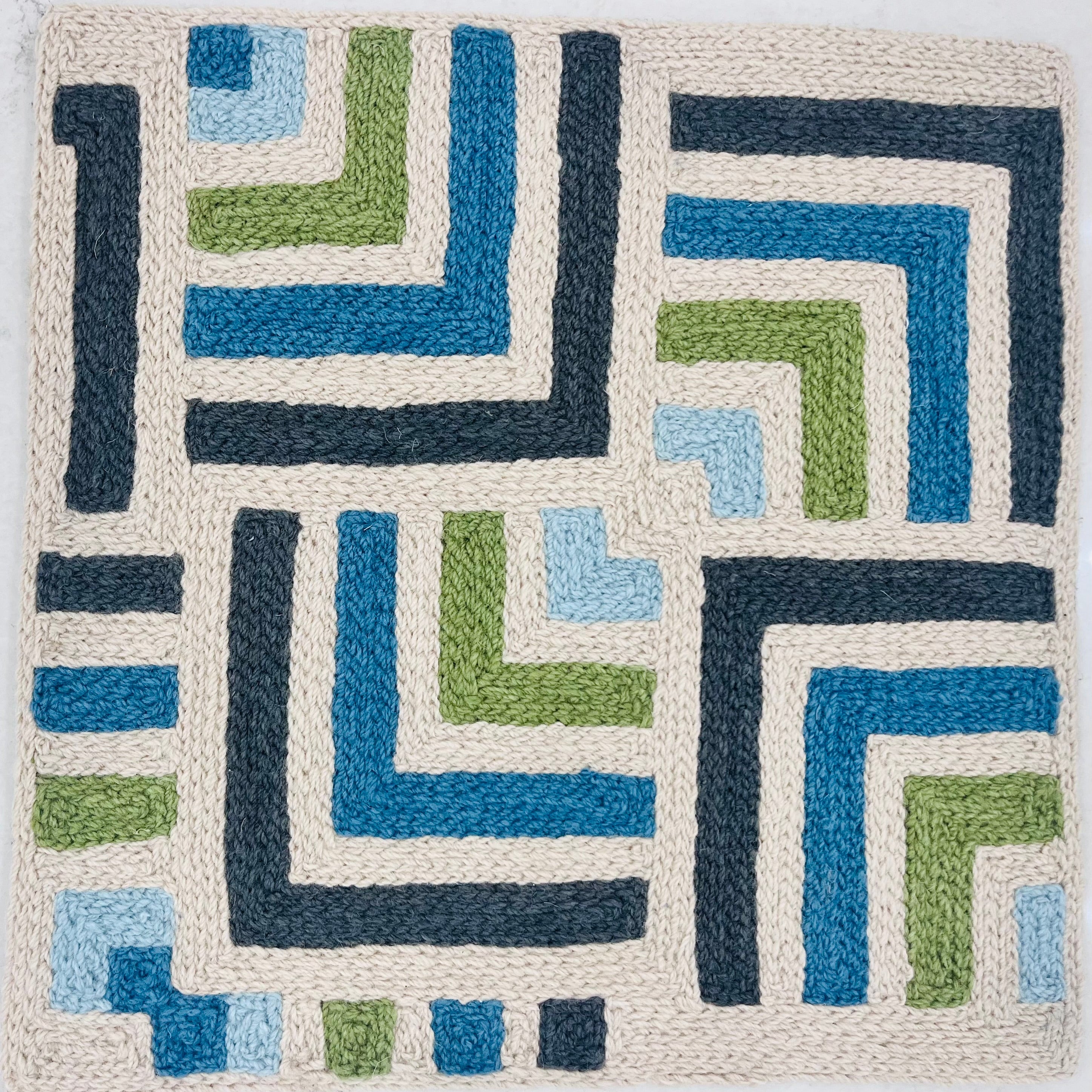 Geometric patterned rug with blue, green, and beige colors on a white background